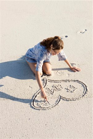 Woman drawing a heart shape on the beach Stock Photo - Premium Royalty-Free, Code: 6108-05866106