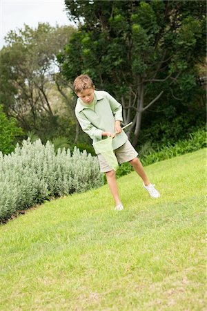 Boy playing with a butterfly net in a garden Stock Photo - Premium Royalty-Free, Code: 6108-05866416