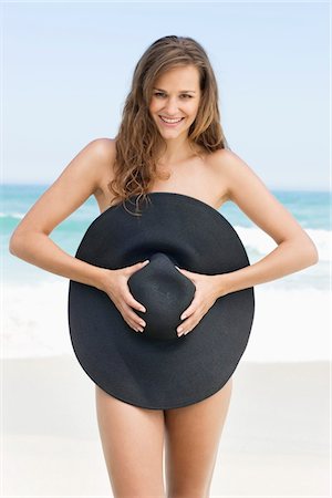 Woman covering her body with a hat Stock Photo - Premium Royalty-Free, Code: 6108-05866587