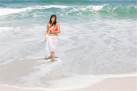 simsearch:6108-05865933,k - Woman walking on the beach and smiling Stock Photo - Premium Royalty-Free, Code: 6108-05866588