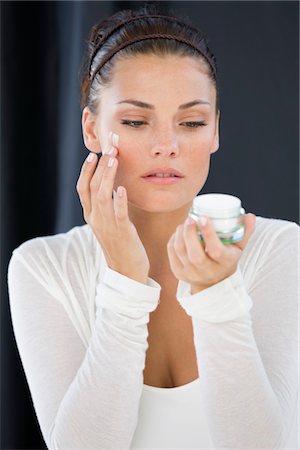 simsearch:6108-08637252,k - Woman applying cream on her face Stock Photo - Premium Royalty-Free, Code: 6108-05866518