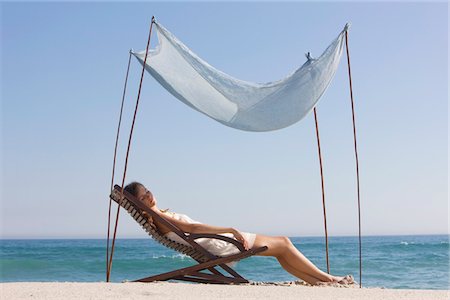 Woman resting in a deck chair under a canopy Stock Photo - Premium Royalty-Free, Code: 6108-05866521