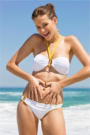 five senses aging - Woman making a heart shape with her finger on her stomach Stock Photo - Premium Royalty-Free, Code: 6108-05866530