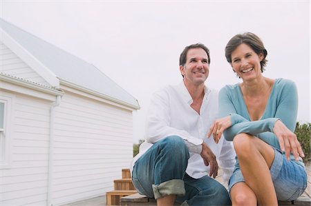real estate people eye contact - Couple sitting together and smiling Stock Photo - Premium Royalty-Free, Code: 6108-05866757