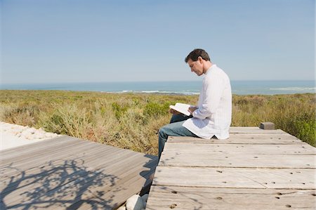 seul (solitude) - Homme assis sur un trottoir de bois et de lire un livre Photographie de stock - Premium Libres de Droits, Code: 6108-05866737