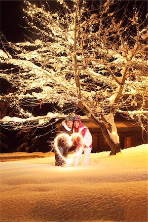 Young couple making heart shape with sparkler by night Stock Photo - Premium Royalty-Free, Code: 6108-05867006