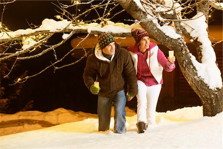 Young couple holding candles, walking in snow by night Stock Photo - Premium Royalty-Free, Code: 6108-05867020