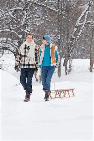 simsearch:6108-05867016,k - Young couple walking in snow pulling a sled Fotografie stock - Premium Royalty-Free, Codice: 6108-05867025