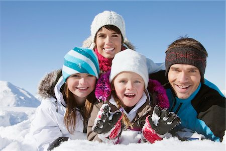 simsearch:6108-05867178,k - Parents and children lying in snow, smiling at camera Fotografie stock - Premium Royalty-Free, Codice: 6108-05867164