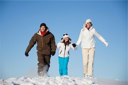 simsearch:6108-05867178,k - Couple and daughter in ski wear walking in snow Fotografie stock - Premium Royalty-Free, Codice: 6108-05867166