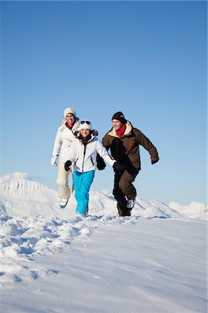 simsearch:6108-05867178,k - Couple and daughter in ski wear running in snow Fotografie stock - Premium Royalty-Free, Codice: 6108-05867186