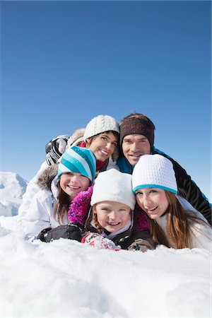 simsearch:6108-05867178,k - Happy family lying in snow, smiling at camera Fotografie stock - Premium Royalty-Free, Codice: 6108-05867192