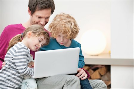 father daughter computer - Close-up of a man assisting his son and daughter in using a laptop Stock Photo - Premium Royalty-Free, Code: 6108-05867368