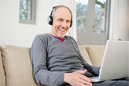 surfer sur internet - Homme à l'aide d'un ordinateur portable et d'écouter de la musique Photographie de stock - Premium Libres de Droits, Code: 6108-05867457