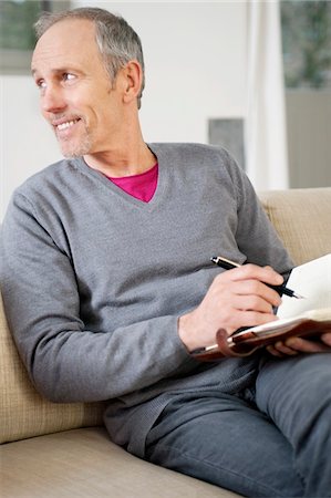 Man writing in a personal organizer Stock Photo - Premium Royalty-Free, Code: 6108-05867456