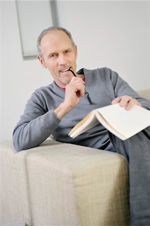 Portrait of a man holding a book and smiling Stock Photo - Premium Royalty-Free, Code: 6108-05867472