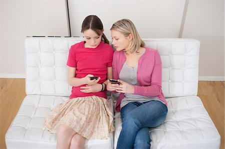 Woman with her daughter text messaging on mobile phones Stock Photo - Premium Royalty-Free, Code: 6108-05867407