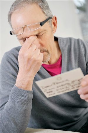 schlechte neuigkeiten - Man looking serious while reading a postcard Foto de stock - Sin royalties Premium, Código: 6108-05867430