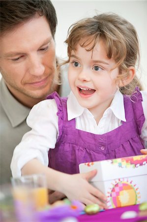 Girl holding her birthday present with her father Stock Photo - Premium Royalty-Free, Code: 6108-05867685