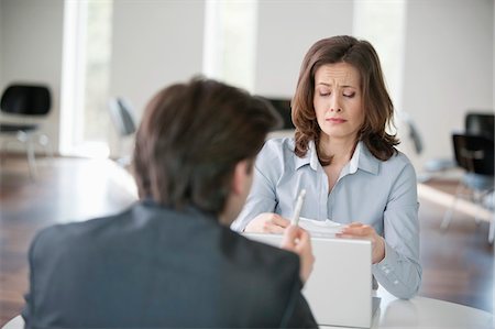 Businesswoman upset while looking at a bill Stock Photo - Premium Royalty-Free, Code: 6108-05868086