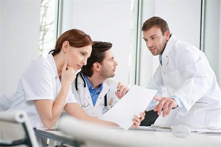 female doctors and male medical exam photos - Three doctors examining a medical report Stock Photo - Premium Royalty-Free, Code: 6108-05868009