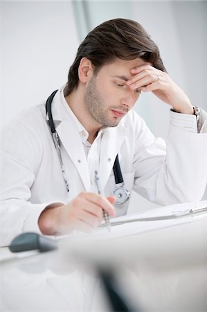 Male doctor sitting in his office and looking upset Stock Photo - Premium Royalty-Free, Code: 6108-05868016