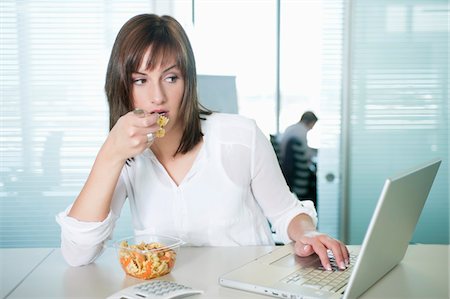 pasta woman - Businesswoman eating pasta and using a laptop Stock Photo - Premium Royalty-Free, Code: 6108-05868354