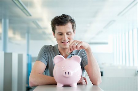 piggy bank and smiling - Businessman inserting a coin into a piggy bank Stock Photo - Premium Royalty-Free, Code: 6108-05868467