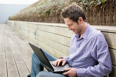 surfing the net - Homme utilisant un ordinateur portable sur un trottoir de bois Photographie de stock - Premium Libres de Droits, Code: 6108-05868540