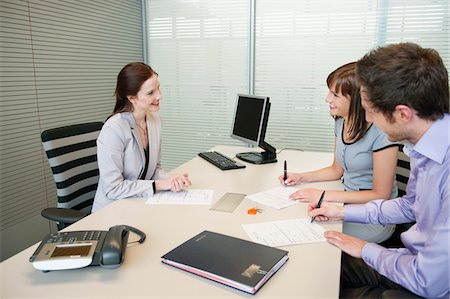 Couple signing agreement form in a real estate agent's office Stock Photo - Premium Royalty-Free, Code: 6108-05868665