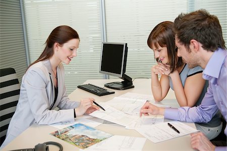 Female real estate agent showing a brochure to a couple Stock Photo - Premium Royalty-Free, Code: 6108-05868671