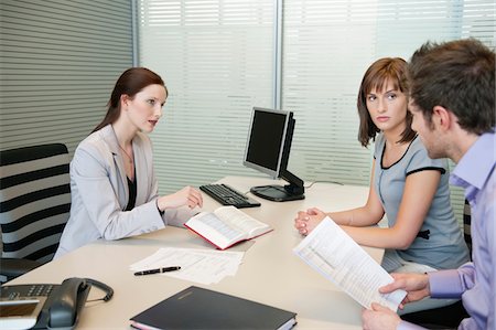 financial advisor talking with clients - Female real estate agent showing a book to a couple Stock Photo - Premium Royalty-Free, Code: 6108-05868632