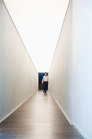Businessman walking in the corridor of an office Stock Photo - Premium Royalty-Free, Code: 6108-05868772