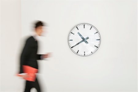 past time - Businessman walking in front of a clock Stock Photo - Premium Royalty-Free, Code: 6108-05868786