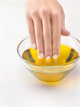 Close-up of woman's hand in bowl of olive oil Stock Photo - Premium Royalty-Free, Code: 6108-05869459