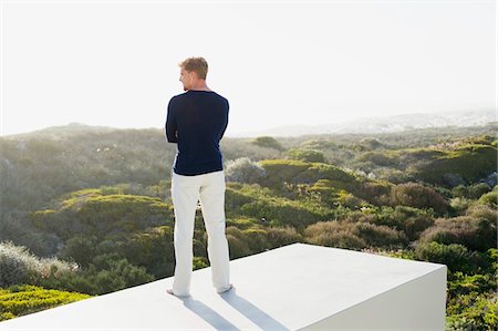 people house backside - Young man looking at view from the terrace of a house Stock Photo - Premium Royalty-Free, Code: 6108-05869670