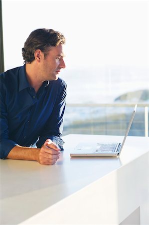 Side profile of a mid adult man looking at a laptop Stock Photo - Premium Royalty-Free, Code: 6108-05869674