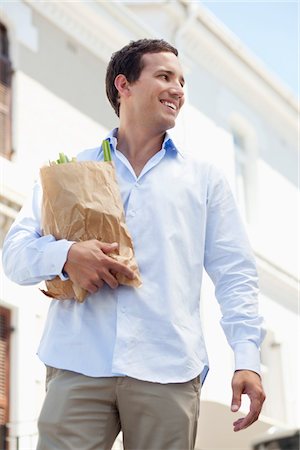 Mid adult man holding a paper bag full of vegetables and smiling Stock Photo - Premium Royalty-Free, Code: 6108-05869616