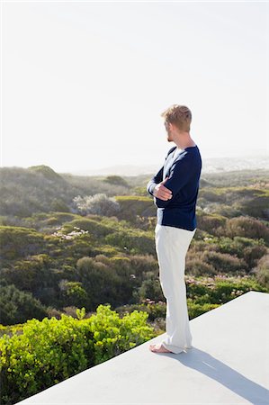 Young man looking at view from the terrace of a house Stock Photo - Premium Royalty-Free, Code: 6108-05869629