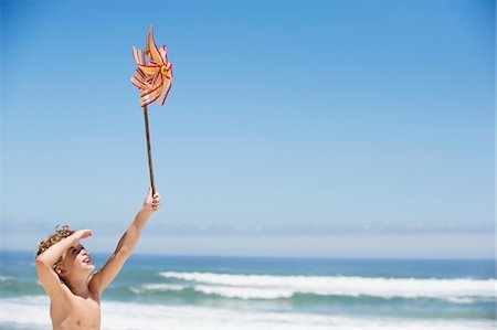 simsearch:6108-05869723,k - Boy holding a pinwheel on the beach Fotografie stock - Premium Royalty-Free, Codice: 6108-05869750