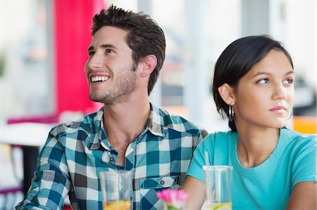 relationship problem - Man smiling with his girlfriend looking sad in a restaurant Stock Photo - Premium Royalty-Free, Code: 6108-05869840