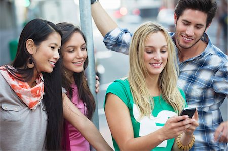 Friends using a mobile phone outdoors Stock Photo - Premium Royalty-Free, Code: 6108-05869870