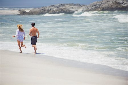 Rear view of a couple running on the beach Stock Photo - Premium Royalty-Free, Code: 6108-05869978