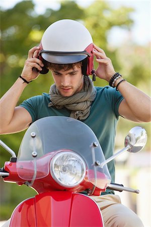 Young man wearing helmet sitting on scooter Stock Photo - Premium Royalty-Free, Code: 6108-05869915