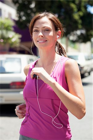 Beautiful young woman listening to mp3 player while jogging Foto de stock - Sin royalties Premium, Código: 6108-05870034