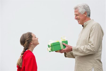 Senior man giving gift to his granddaughter Foto de stock - Sin royalties Premium, Código: 6108-05870149