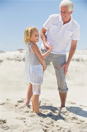 simsearch:6108-05870126,k - Senior man smiling with his granddaughter on the beach Stock Photo - Premium Royalty-Free, Code: 6108-05870158