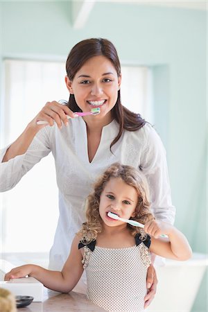 Portrait of a young woman and her daughter brushing teeth Stock Photo - Premium Royalty-Free, Code: 6108-05870184