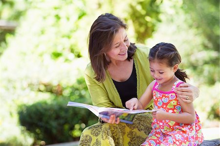 reading book outdoors - Woman with her granddaughter reading a book Stock Photo - Premium Royalty-Free, Code: 6108-05870123