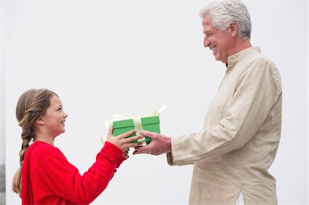 Senior man giving gift to his granddaughter Foto de stock - Sin royalties Premium, Código: 6108-05870132